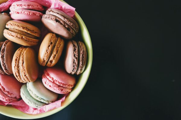 A bowl of assorted colorful macarons on a dark table. Perfect for dessert inspiration.