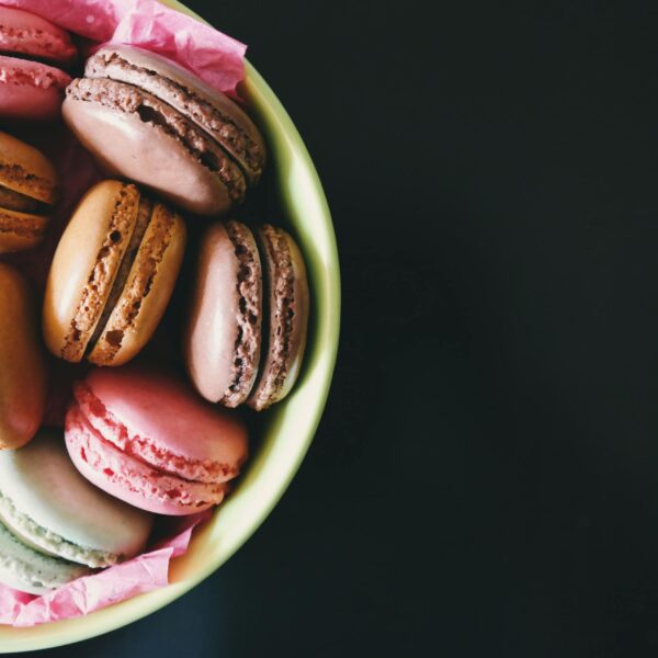 A bowl of assorted colorful macarons on a dark table. Perfect for dessert inspiration.