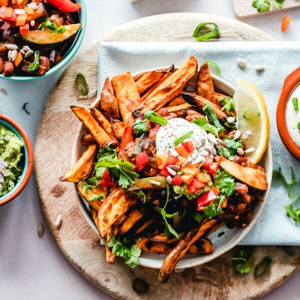 A vibrant platter of savory sweet potato fries with fresh toppings, perfect for a tasty snack.