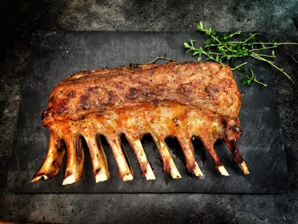 Delicious grilled spare ribs served with fresh herbs on a stone surface.