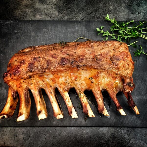 Delicious grilled spare ribs served with fresh herbs on a stone surface.